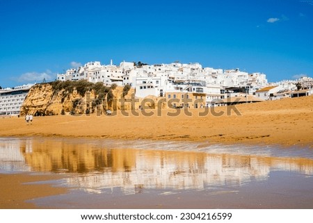 Great view of Fisherman Beach, Praia dos Pescadores, with whitewashed houses on cliff, reflecting on the sea, blue sky, summer time, Albufeira, Algarve, Portugal