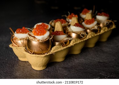 Great view on delicious eggs stuffed with red caviar tasty and healthy dish serving in golden shell in egg box on grey table