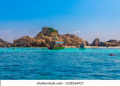 Great view of Tokong Burung (Bird Island), an uninhabited island near Perhentian Kecil in Malaysia. Motorboats are anchoring and tourists are snorkeling around the island in crystal clear water.