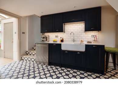 Great Wratting, Suffolk - August 21 2019: Cottage Kitchen With Distinctive Traditional Tile Floor And Striking Black Coloured Cabinetry Incorporating A Butler Sink.