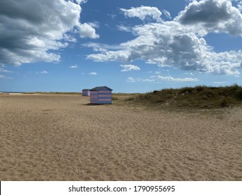 Great Yarmouth Beach Cabins In A Summer Day, Traditional UK Cabin On An English East Coast, Blue And Pink Horizontal Stripes, Sky With Clouds No People, Large Stretch Of Sand, UK Beaches