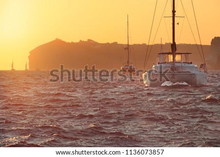 Greece, catamaran boats in the famous sunset of greek island Santorini