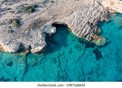 Greece. Cyclades. Seascape with caves and rocks over green emerald clear sea water, Small Cyclades island, aerial drone top down view