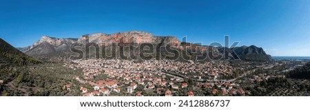 Greece, Leonidio, Arcadia, Peloponnese. Aerial drone panoramic view of town with traditional building, mountain, cliff, sea water, blue sky. Banner