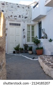 Greece, Melos island, Chora town, Plaka. Entrance of building outdoor pot, amphora with plant on empty cobblestone narrow alley. Destination Milos Cyclades. Vertical - Shutterstock ID 2124185207