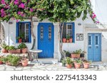 Greece. Tinos island of art, Cycladic architecture at Pyrgos village, bougainvillea on whitewashed wall, blue door and windows, sunny day.