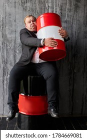 greedy caucasian fat oil tycoon hugs oil barrel. handsome businessman in formal wear engaged in oil production - Shutterstock ID 1784669081