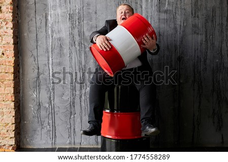 greedy caucasian fat oil tycoon hugs oil barrel. handsome businessman in formal wear engaged in oil production