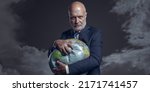 Greedy corporate businessman crushing a globe: earth exploitation and power concept