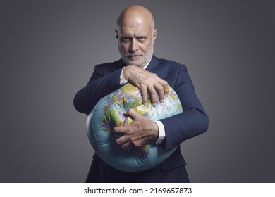 Greedy Corporate Businessman Crushing A Globe: Earth Exploitation And Power Concept