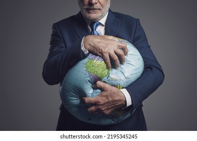 Greedy Corporate Businessman Crushing A Globe: Earth Exploitation And Power Concept