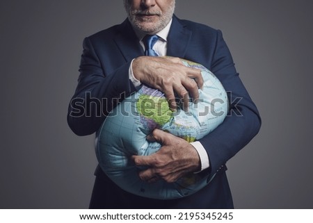 Greedy corporate businessman crushing a globe: earth exploitation and power concept