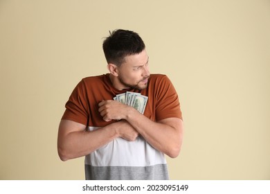 Greedy man hiding money on beige background