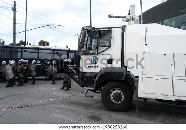 Greek anti-riot police officers\
walk next to a truck-mounted water cannon as they disperse\
protesters during a demonstration in Athens, Greece on May 15,\
2021.