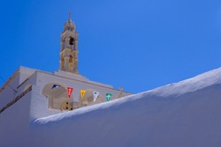 Greek Church With Colorful Fags Over Blue Sky On Tinos Island, Greece