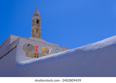 Greek church with colorful fags over blue sky on Tinos Island, Greece