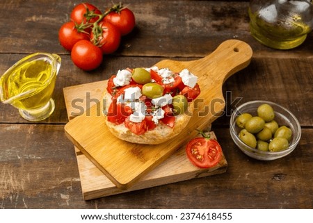 Greek cuisine, dakos with fresh tomatoes and olives, wooden table.