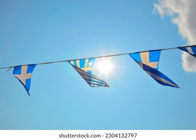 Greek flag on the street, blue and white national colors. Patriotic garland, triangular bunting. The sky and clouds over Athens display colors of Greek flag too. Celebration in Greece. - Powered by Shutterstock