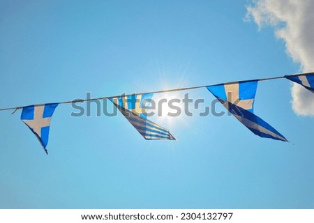 Greek flag on the street, blue and white national colors. Patriotic garland, triangular bunting. The sky and clouds over Athens display colors of Greek flag too. Celebration in Greece.