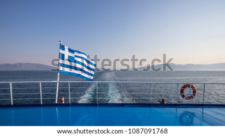Greek flag waving on a ferry boat crossing the sea