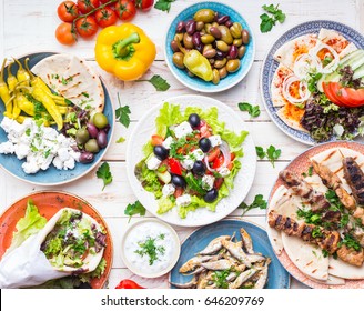 Greek food background. Meze, gyros, souvlaki, fish, pita, greek salad, tzatziki, assortment of feta, olives and vegetables. Traditional different greek dishes set. Top view. Food for share. Close-up - Shutterstock ID 646209769