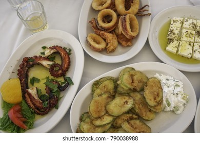 Greek Food Close Up Top View.  Taverna Style Food With Octopus And Squid Seafood, Feta Cheese With Oregano And Olive Oil And Fried Zucchini With Tzatziki Sauce.