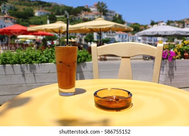 Greek Frappe Coffee And Ashtray On A Table At The Port Of Evdilos, Ikaria, North Aegean Islands