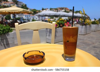 Greek Frappe Coffee And Ashtray On A Table, Closer View. At The Port Of Evdilos, Ikaria, North Aegean Islands