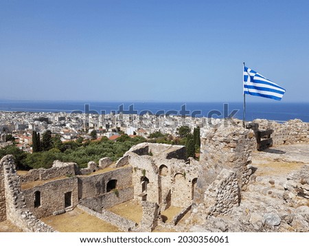 Greek glad flutters on top of an old castle overlooking the city of Patras