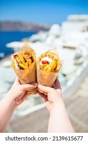 Greek gyros wrapped in pita bread photographed against traditional greek town with white houses
