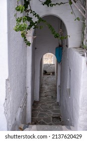 Greek Island, Cyclades. Stair drives to narrow cobblestone street and then to light, whitewashed arch wall covers the alley. Cycladic architecture. Vertical
