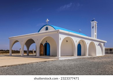 Greek Orthodox chapel of Agia Thekla with turquoise dome with cross, white walls, high bell tower, arched door and blue windows with shutters, arches and column at entrance (Sotira, Ayia Napa, Cyprus) - Powered by Shutterstock