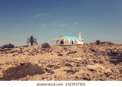 Greek Orthodox chapel of Agia Thekla with turquoise dome with cross, white walls, high bell tower, arched door and blue windows with shutters, arches and column at entrance (Sotira, Ayia Napa, Cyprus) - Powered by Shutterstock