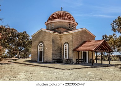 Greek Orthodox Church of Petounda is Made of Yellow Lime Brick with Round Windows, an Arched Entrance, Wooden Canopy and Cross on Red Tiled Roof in Shade of Green Trees (Mazotos, Larnaca, Cyprus) - Powered by Shutterstock