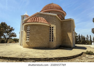 Greek Orthodox Church of Petounda is Made of Yellow Lime Brick with Round Windows, an Arched Entrance, Wooden Canopy and Cross on Red Tiled Roof in Shade of Green Trees (Mazotos, Larnaca, Cyprus) - Powered by Shutterstock