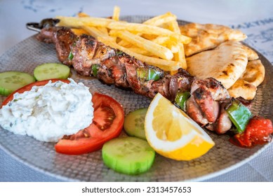 Greek pork Souvlaki with tzatziki sauce and fresh vegetables, grilled kebabs - Powered by Shutterstock