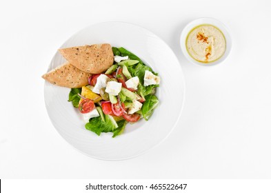 Greek Salad With Feta Cheese, Ligurian Olives And Tortilla Pea And Hummus On A Plate On A White Background, Top View