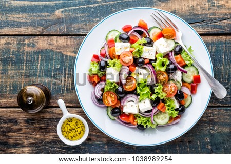 Greek salad of fresh cucumber, tomato, sweet pepper, lettuce, red onion, feta cheese and olives with olive oil. Healthy food, top view