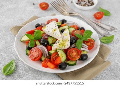 Greek salad of fresh juicy vegetables, feta cheese, herbs and olives on a white plate on a light concrete background. Healthy food. Copy space, top view - Powered by Shutterstock