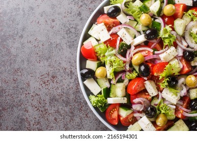 Greek Salad With Fresh Vegetables, Feta Cheese And Black Olives Close-up In A Plate On The Table. Horizontal Top View From Above
