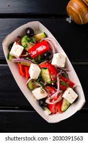 Greek Salad To Go In Paper Box, Greek Salad In A Takeaway Box On A Black Wooden Table. Takeaway Food.