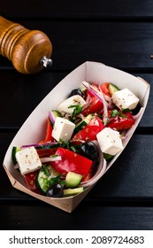 Greek Salad To Go In Paper Box, Greek Salad In A Takeaway Box On A Black Wooden Table. Takeaway Food.