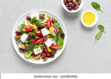 Greek salad with greens, olives and feta chesse on a white plate, top view - Powered by Shutterstock