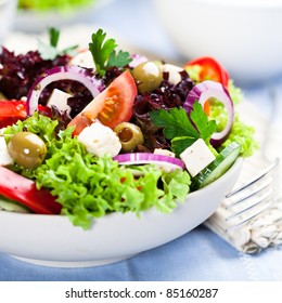 Greek salad with juicy tomatoes, feta cheese,  lettuce, green olives, cucumber, red onion and fresh parsley. Homemade food. Symbolic image. Concept for a tasty and healthy vegetarian meal. Close up. 
