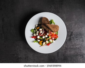 Greek Salad With Roasted Garlic Bread On The White Plate