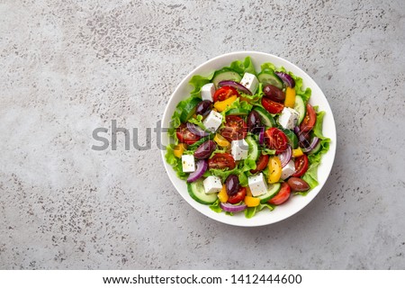 greek salad ( tomato, cucumber, bel pepper, olives  and feta cheese) in white bowl, top view, copy space
