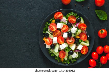 Greek salad with tomato and fresh vegetables in white bowl on dark background. Top view - Shutterstock ID 1714895032