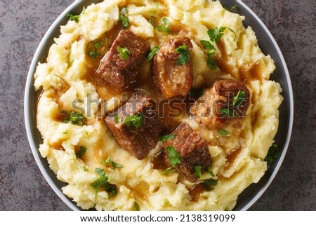 Greek Sofrito Slow braised beef with spicy gravy garnished with mashed potatoes close-up in a plate on the table. horizontal top view from above