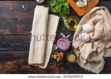 Greek spanakopita ingredients filo spinach eggs feta  top view on dark wooden background space for text