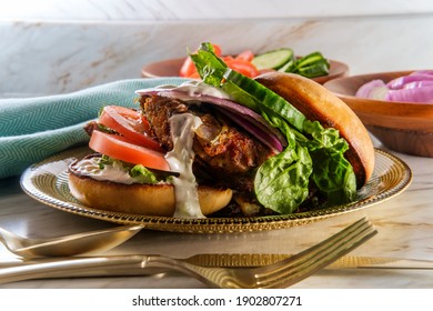 Greek Stuffed Turkey Burger Topped With Cucumber Slices And Tzatziki Yogurt Sauce Served With Mediterranean Street Cart Fried Potatoes With Feta Cheese Olives Herbs And Spices